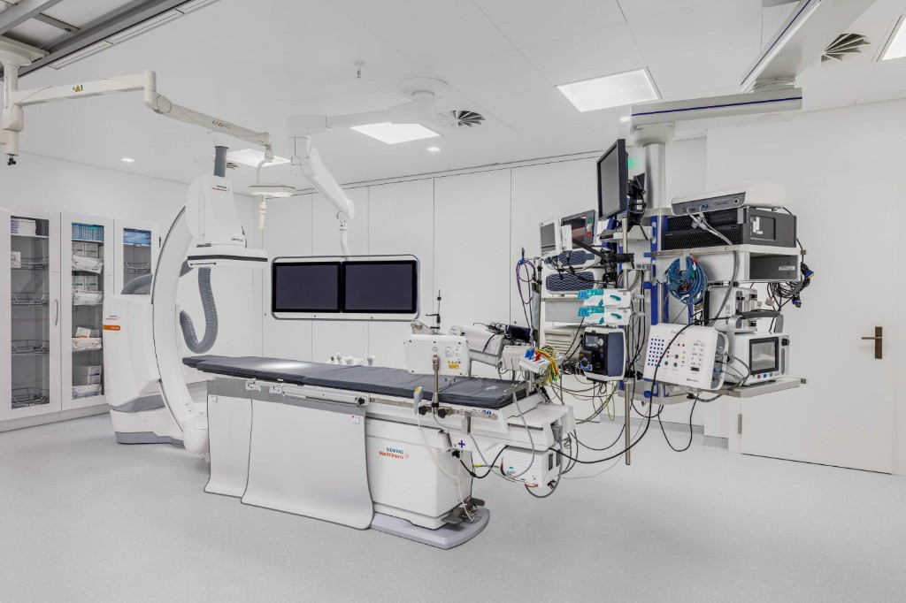 Laboratório de eletrofisiologia com mesa de procedimentos, sistema de fluoroscopia e monitores de mapeamento
